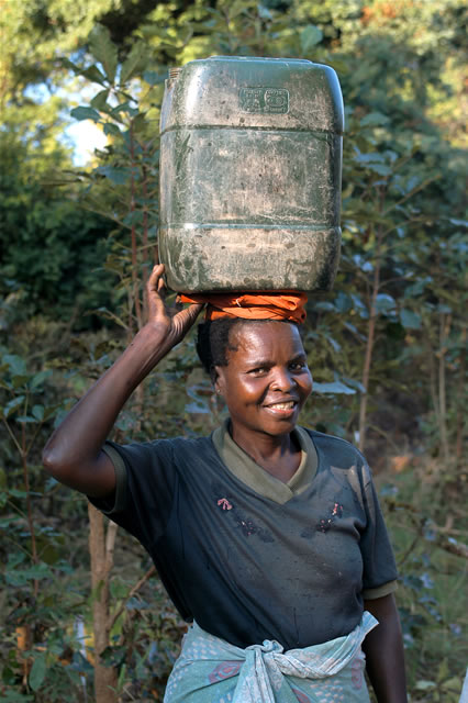 Frau mit Wasserkanister auf dem Kopf